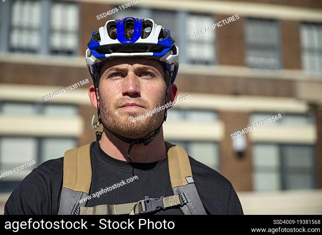 Low angle portrait of a young Caucasian man wearing a helmet, commuting to work