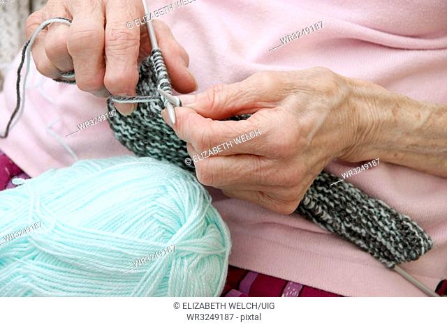 Elderly woman knitting a garment