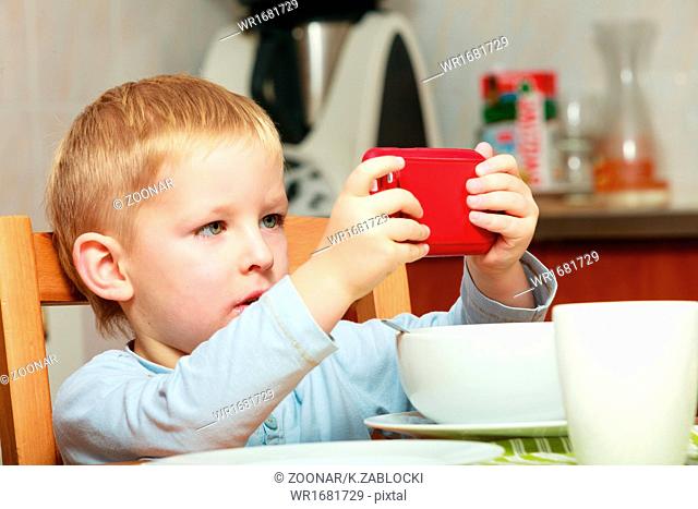 Funny dirty boy child kid taking photo with red mobile phone indoor