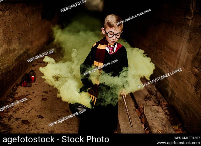Boy with cauldron and magic ward standing amidst yellow in tunnel