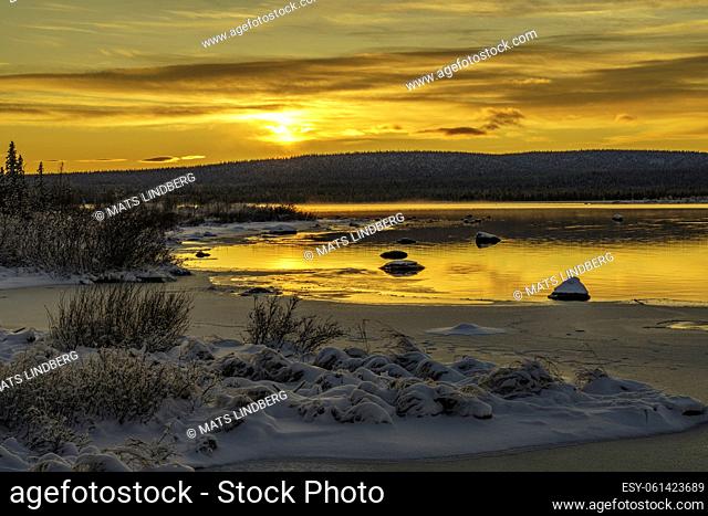 Winter landscape in direct light at sundset, open water with fog over the water, Gällivare, Swedish Lapland, Sweden