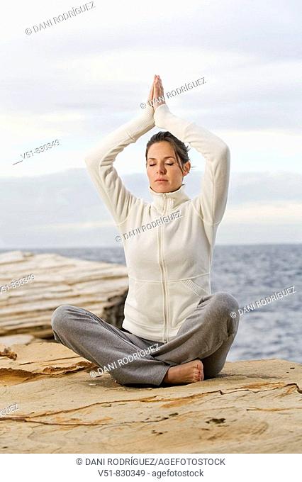 Woman doing yoga in a cliff by the sea