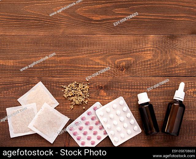 tablets, drops and herbals on a dark wooden background with copy space. Flat lay or top view