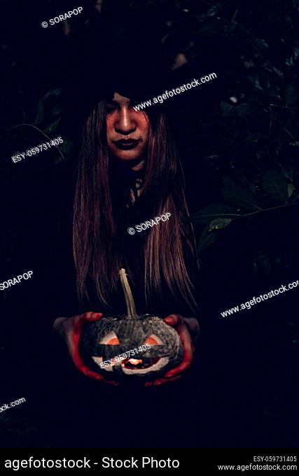 Portrait of woman ghost horror her have pumpkin on hand in forest, halloween day concept