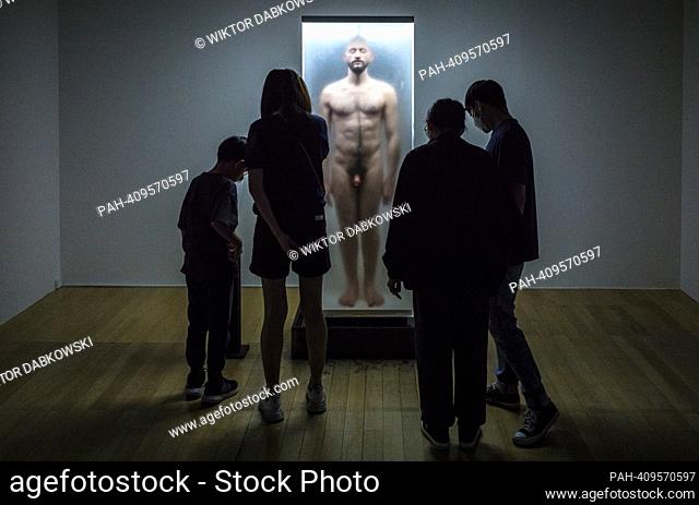 People look at sculpture of a naked man enclosed in a glass display case during the SUPERNATURAL: Sculptural Visions of the Body exhibition in Taipei