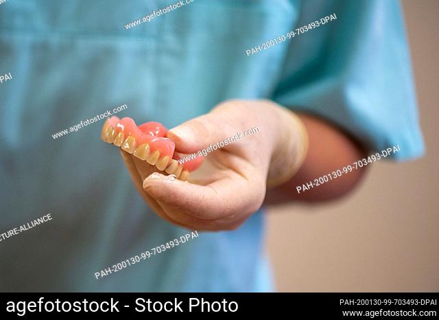 28 January 2020, Saxony-Anhalt, Magdeburg: A dentist checks a resident's dental prosthesis in her treatment room in a retirement home
