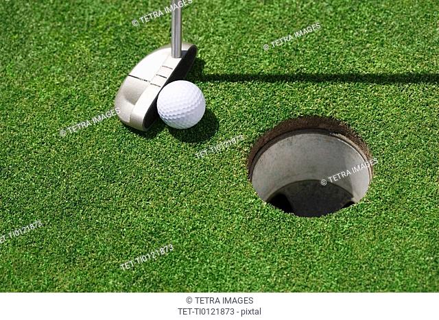 Golf ball near cup on putting green outdoors