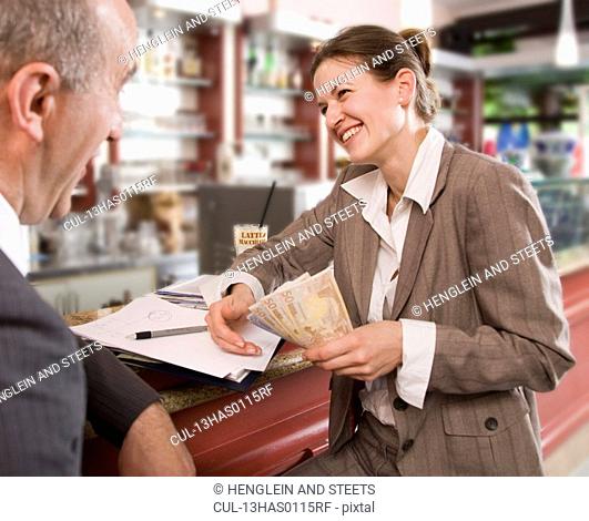 businesswoman paying man in bar