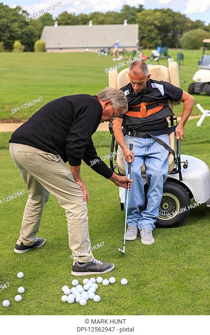 Man with spinal cord injury in an adaptive cart at golf putting green with an instructor
