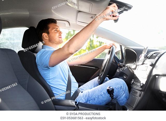 man or car driver adjusting mirror