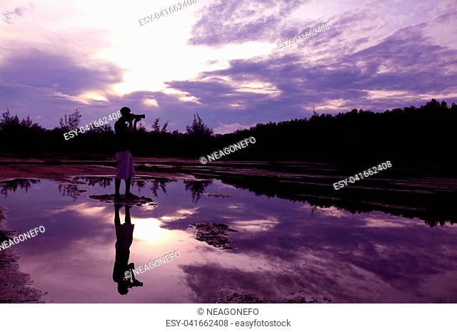 Mirror of purple sky in the morning reflection to the water with shadow of photographer in Thailand
