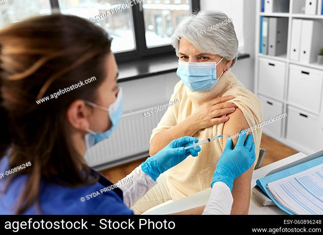 nurse with syringe making injection to woman