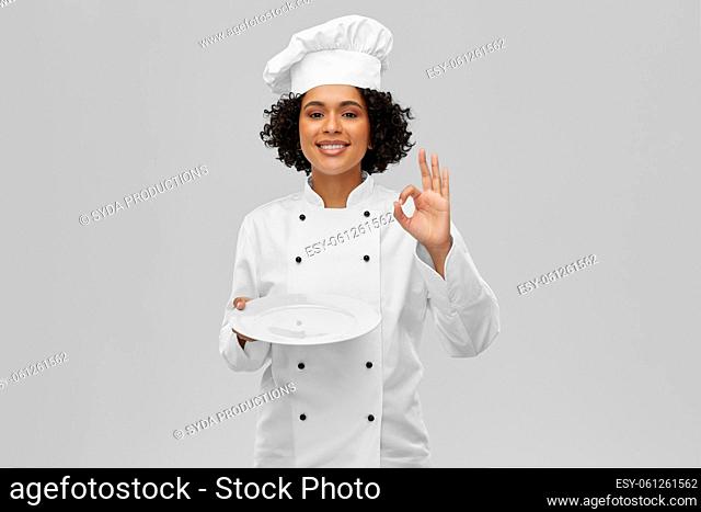 female chef holding plate and showing ok sign