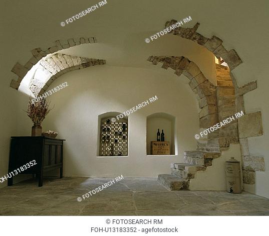 Wine storage in alcoves in cellar with stone floor and steps