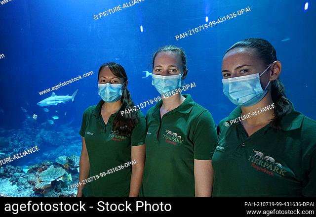 23 June 2021, Hamburg: Animal keeper Annika Höffner (l-r), animal keeper Nele Baumann and trainee Elena Biermann stand in front of the large shark atoll in the...
