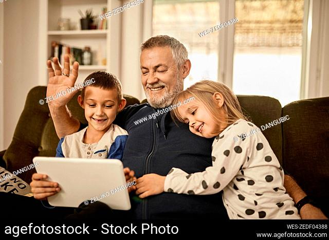 Grandchildren using tablet PC with grandfather at home