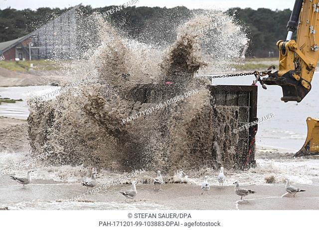 A bulldozer pulls a large metal sieve through washed up sand to extract and clean the sand from potential World War II ammunition for a coastal flood defence...