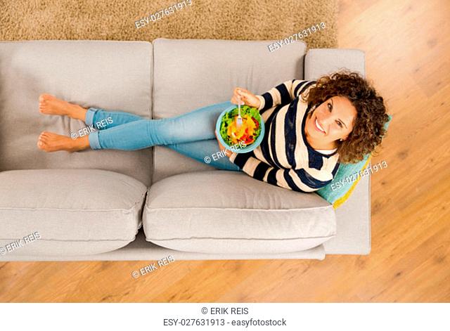 Top view of a beautiful woman on the sofa eating a healthy salade