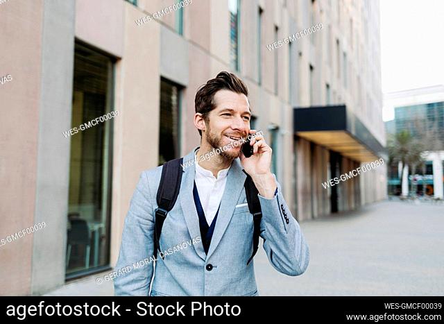 Smiling male professional talking on mobile phone while looking away