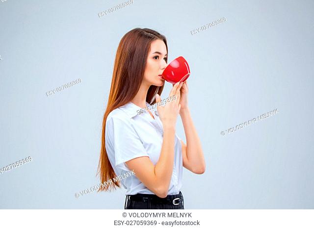 The young business woman i with red cup of coffee on a gray background