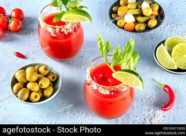 Bloody Mary cocktail with tomato juice, lime, and celery, with olives and chili peppers