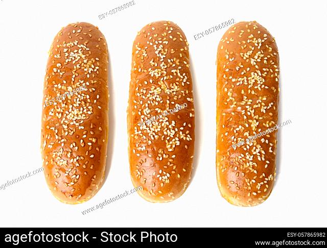 baked oval hot dog bun, baked goods sprinkled with sesame seeds and isolated on white background, top view