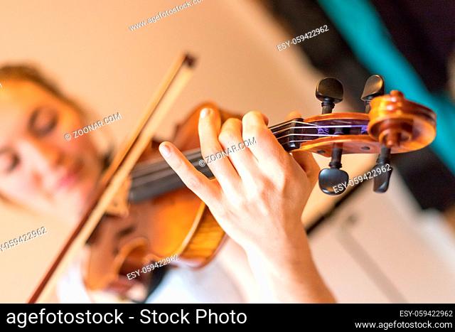 Pretty young girl practices on her violin, acoustic music
