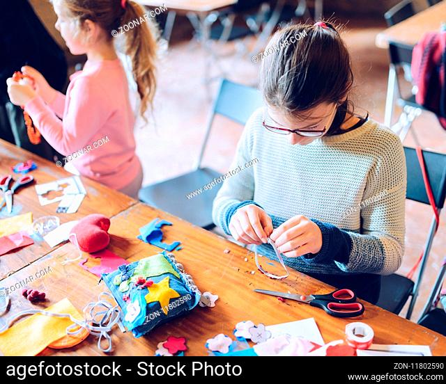 tailor art workshops for children - a girl sewing felt decorations - colorful fabrics lying on a table