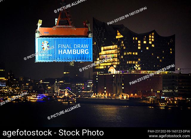 02 December 2023, Hamburg: Soccer: European Championship, draw - preliminary round in Hamburg. A labeled container (""Final Draw Hamburg"") floats on a crane in...