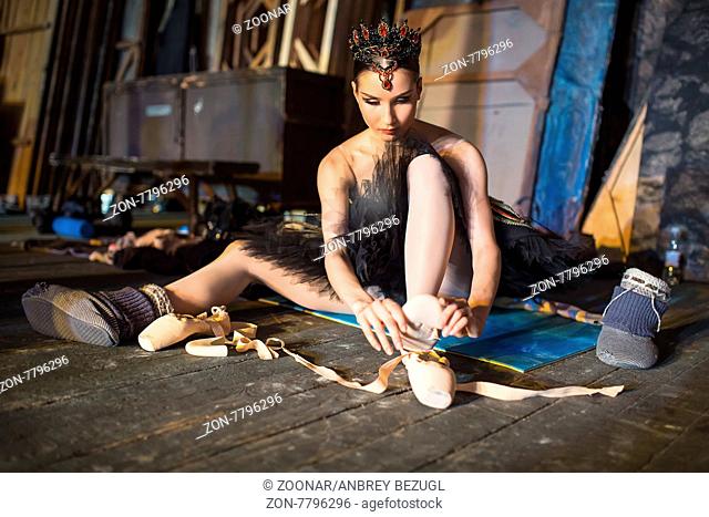 Prima ballerina sitting on the warm-up backstage before going on stage for a solo program on the stage in a performance of Swan Lake, view the profile