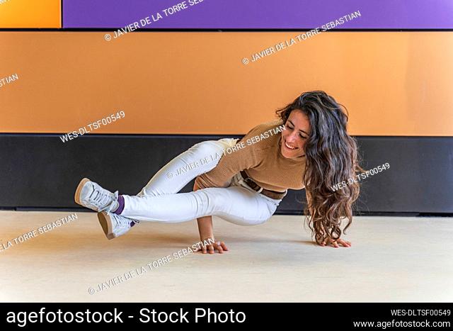 Woman practicing yoga in front of colorful wall