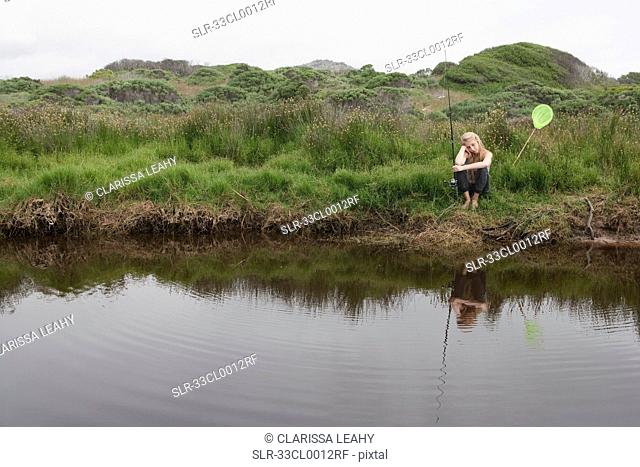 Girl fishing with net in creek