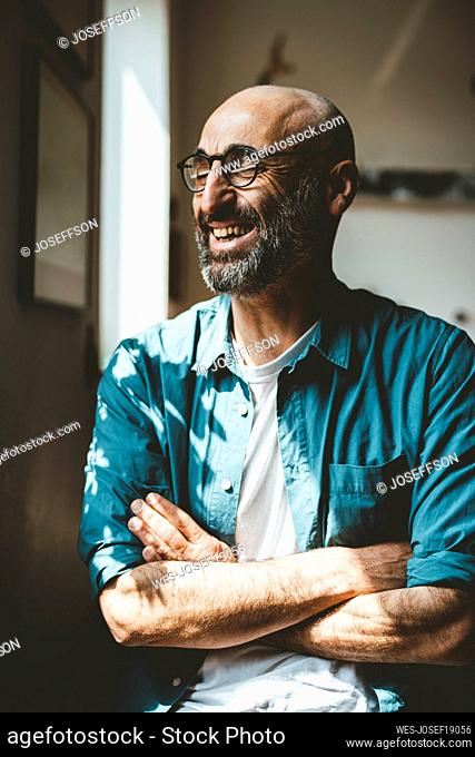 Happy man with arms crossed at home