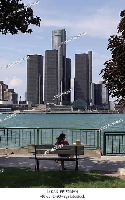Woman sitting on a bench looking at the city of Detroit's skyline as seen from Windsor, Ontario, Canada. Detroit, the cradle of America¿s automobile industry...