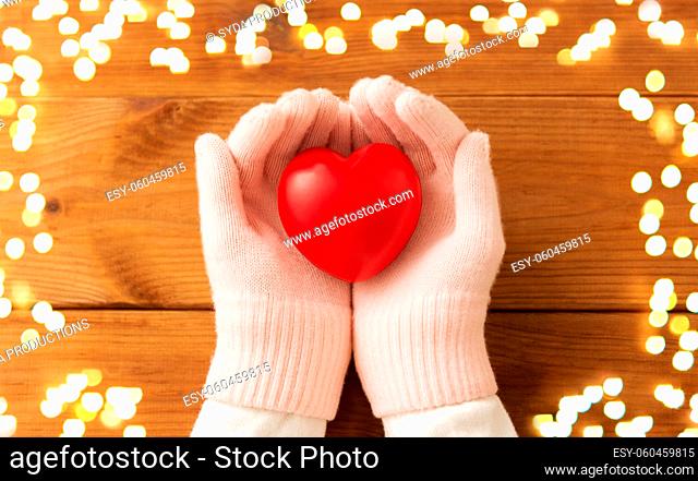 hands in pink woollen gloves holding red heart