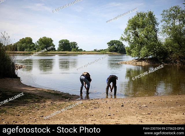PRODUCTION - 31 May 2023, Hamburg: Martin Beckers (r), perennial gardener, and Gerwin Obst, Elbe Habitat Foundation, wash their hands after planting hemlock...
