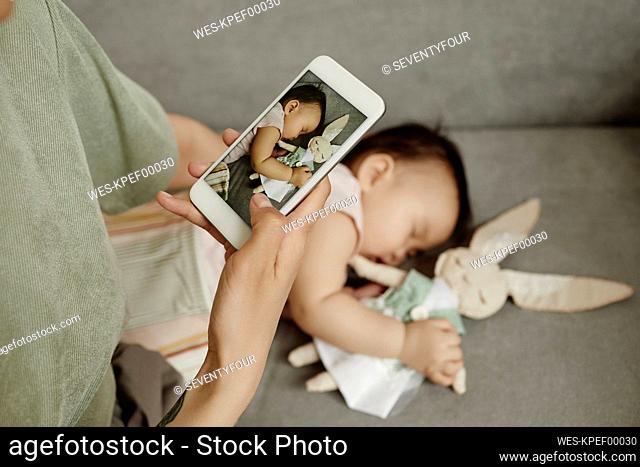 Mother taking picture of daughter sleeping at home