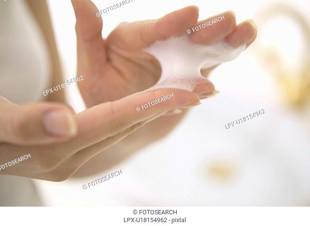 Young woman making soap suds with hands, close up