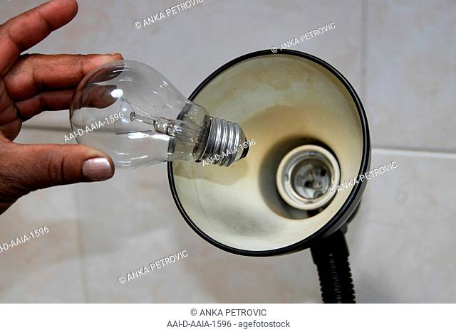 Close-up of hand changing a lightbulb into a desk lamp, South Africa