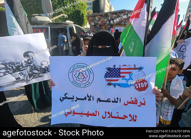 14 July 2022, Palestinian Territories, Gaza City: A Palestinian woman holds a placard as she takes part in a protest against US President Joe Biden's visit to...