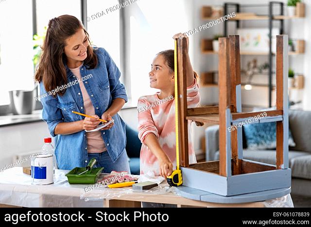 mother and daughter with ruler measuring old table