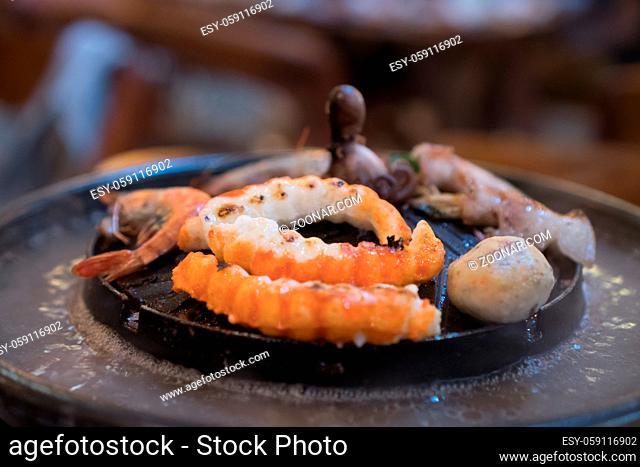 Seafood on steaming and grilling cooker pot over blurred background