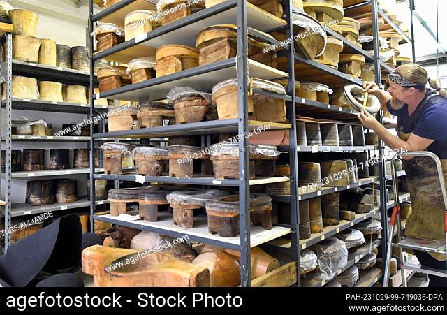 24 October 2023, Thuringia, Altenburg: At Hut und Kostüm GmbH, milliner Thomas Krause searches for a head size for a hat on shelves filled with hundreds of...