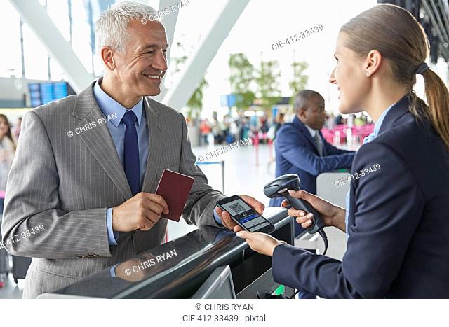 Customer service representative scanning smart phone QR code boarding pass at airport check-in counter