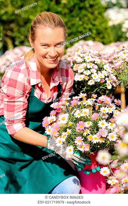 Garden center woman holding potted flowers smiling