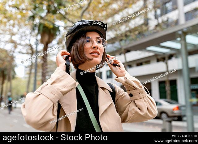 Mid adult woman wearing cycling helmet while standing at street in city