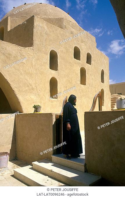 Coptic monastery. Sunbaked mud structure. Dome. Man in black robes