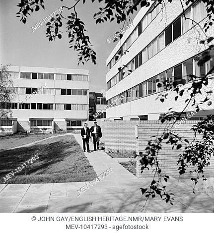 Two men walking in front of a block of a flats built in the Brutalist style on a modern estate in Hillingdon