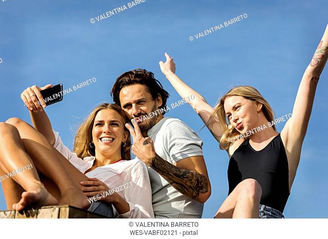 Friends having fun on a rooftop terrace, taking selfies