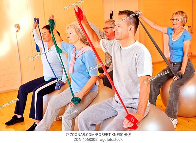 Gruppe macht gemeinsam Seniorensport mit Gymnastikband im Fitnesscenter